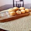 banana bread muffins on a wooden cutting board on a tan mat on a dark table