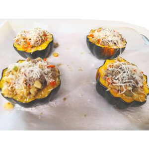 Filling added to acorn squash and topped with parmesan cheese