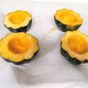 Squash cut in half on baking sheet drizzled with olive oil
