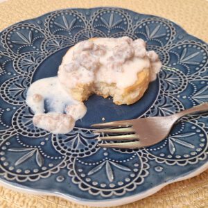 Sausage gravy over biscuit on a blue plate