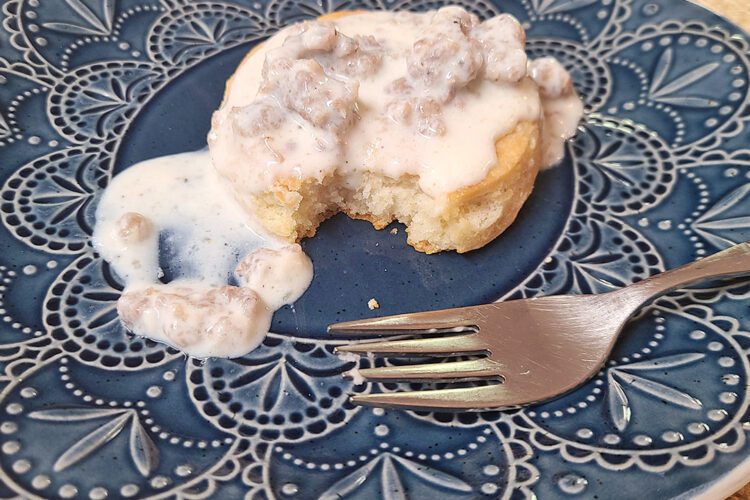 Sausage gravy over biscuit on a blue plate