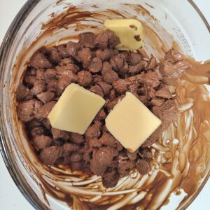 milk chocolate chips partially melted with butter now added in a glass bowl