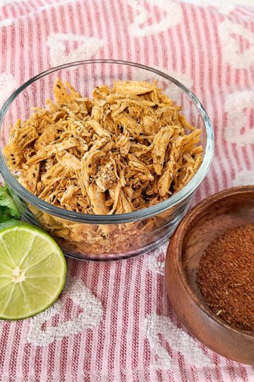 Shredded Chicken with a lime, fresh cilantro, and taco seasoning in a wood bowl