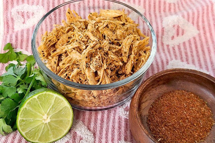 Shredded Chicken with a lime, fresh cilantro, and taco seasoning in a wood bowl