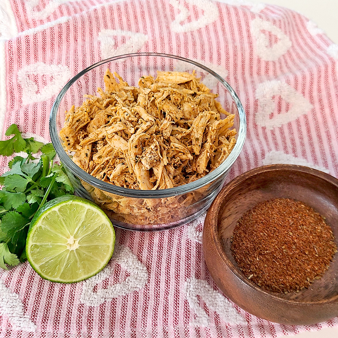 Shredded Chicken with a lime, fresh cilantro, and taco seasoning in a wood bowl