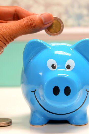 blue piggy bank with hand putting in a coin