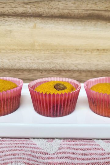 pumpkin chocolate chip muffins on a white oval dish with a wood background