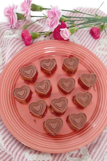 Peanut butter filled chocolates on round plate with towel and flowers around