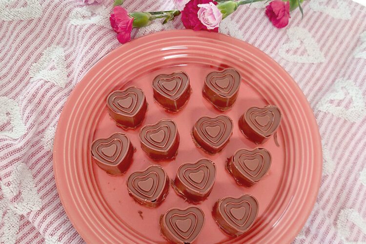 Peanut butter filled chocolates on round plate with towel and flowers around