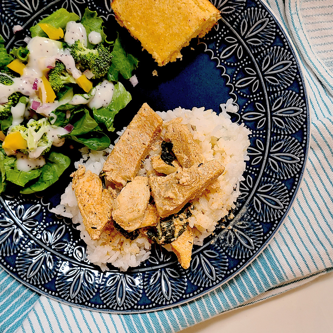 Chicken & Spinach with a Lemon Cream Sauce plated with a salad and corn bread on a blue plate