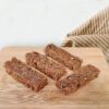 protein bars on wood cutting board with a brown striped cloth napkin behind