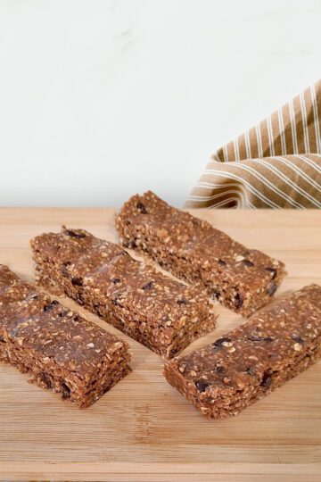 protein bars on wood cutting board with a brown striped cloth napkin behind