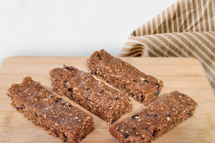 protein bars on wood cutting board with a brown striped cloth napkin behind