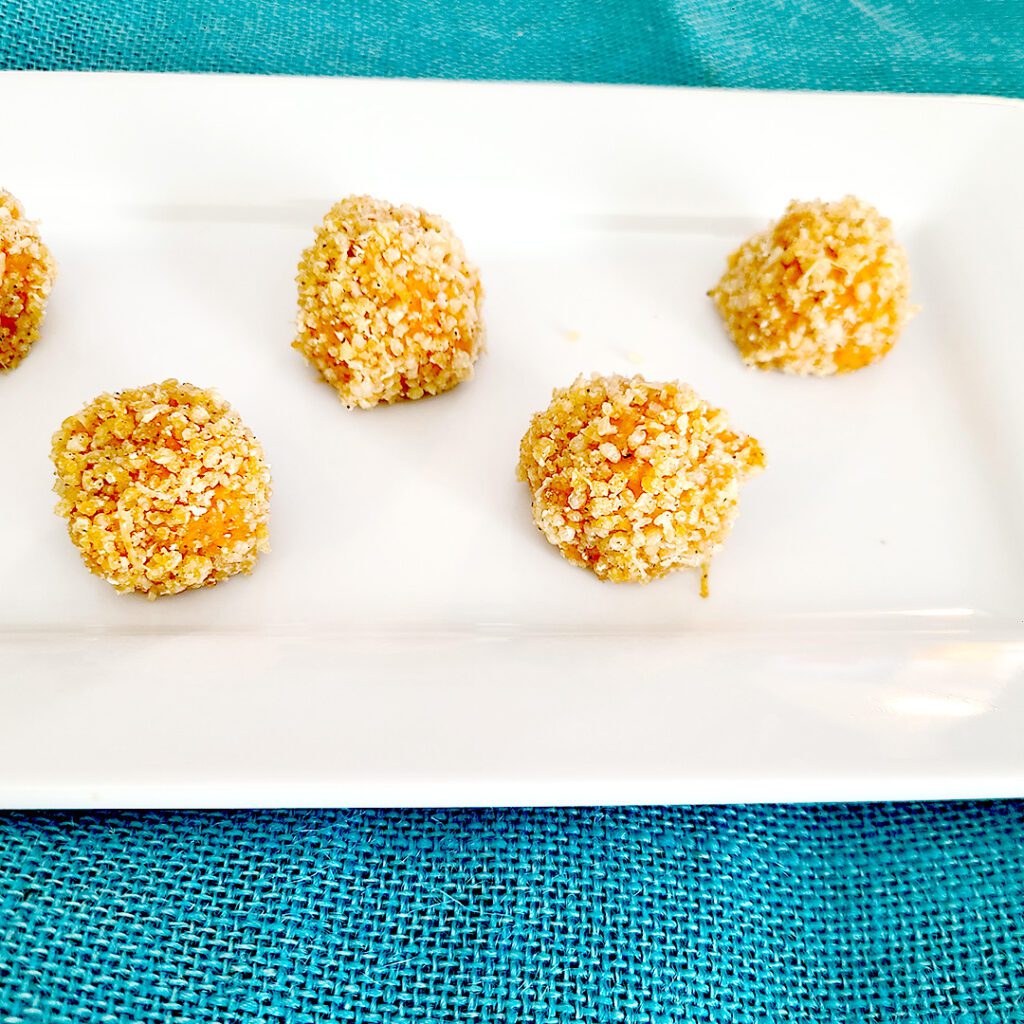 savory sweet potato balls on white platter with teal cloth underneath