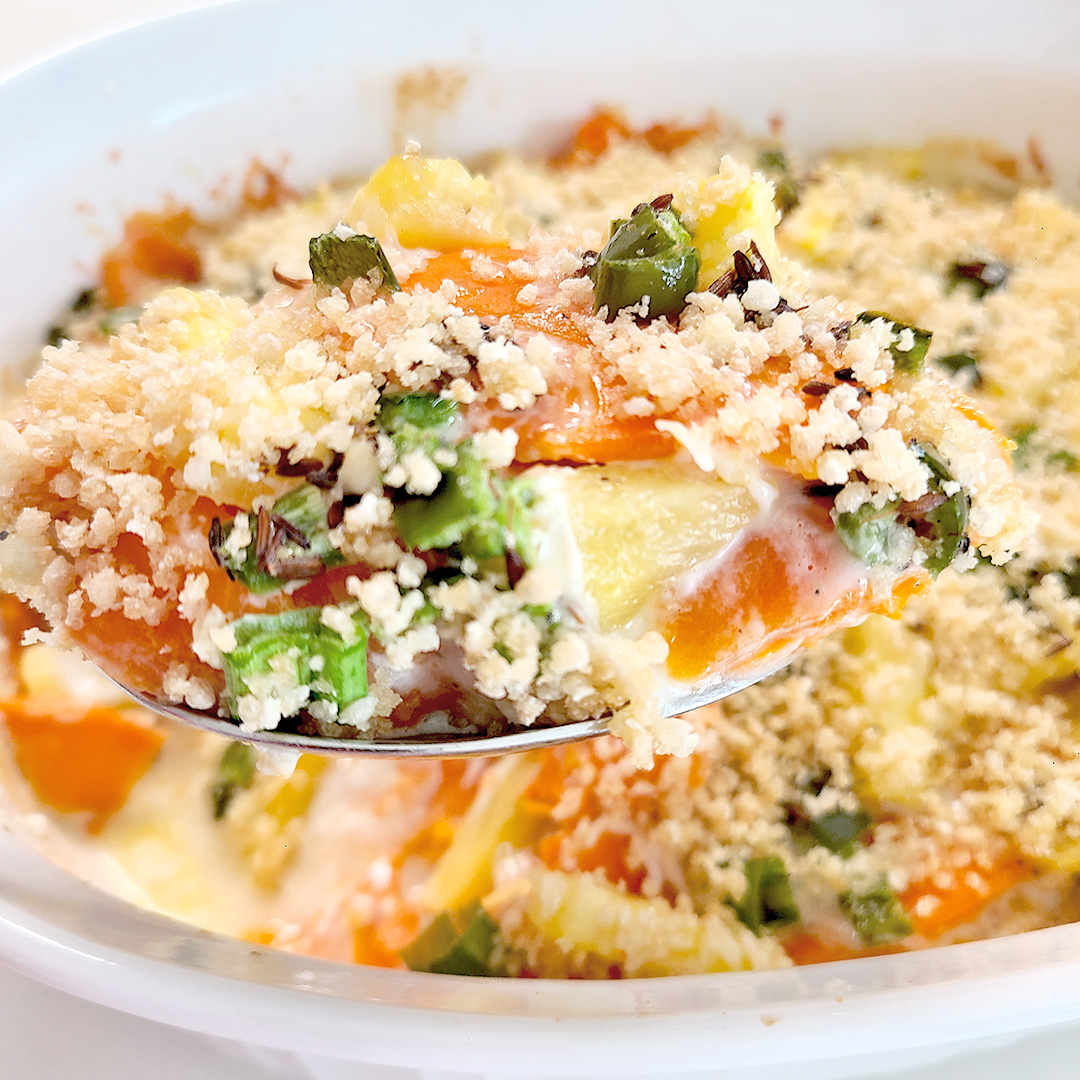 spicy sweet potato and pineapple casserole in a white dish with some up close on a spoon