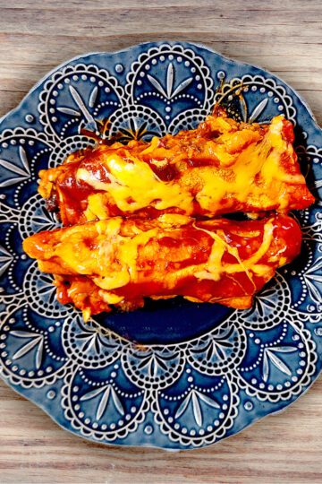 two beef enchiladas on a blue plate with a wooden background