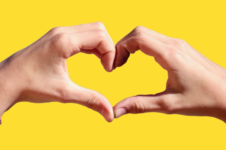 two hands making a heart with a yellow background