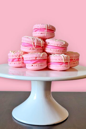 strawberry macaroons on white cake stand with pink and brown background