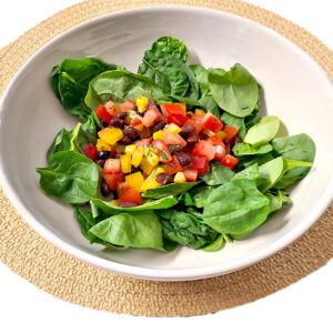 spinach salad with cilantro-lime vinaigrette in a white bowl on a light brown circular mat