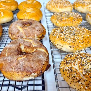 gluten free bagels on a cooling rack; cinnamon sugar, plain, and everything bagel