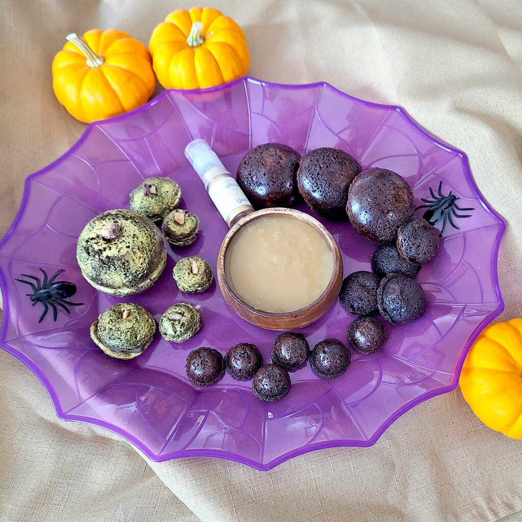 Pumpkin shaped caramel filled brownies coated in edible gold dust on a purple plate with pumpkins around it