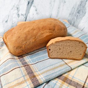 Emma's gluten free loaf bread on a plaid blue and brown tea towel on the counter