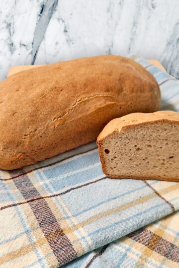 Emma's gluten free loaf bread on a plaid blue and brown tea towel on the counter