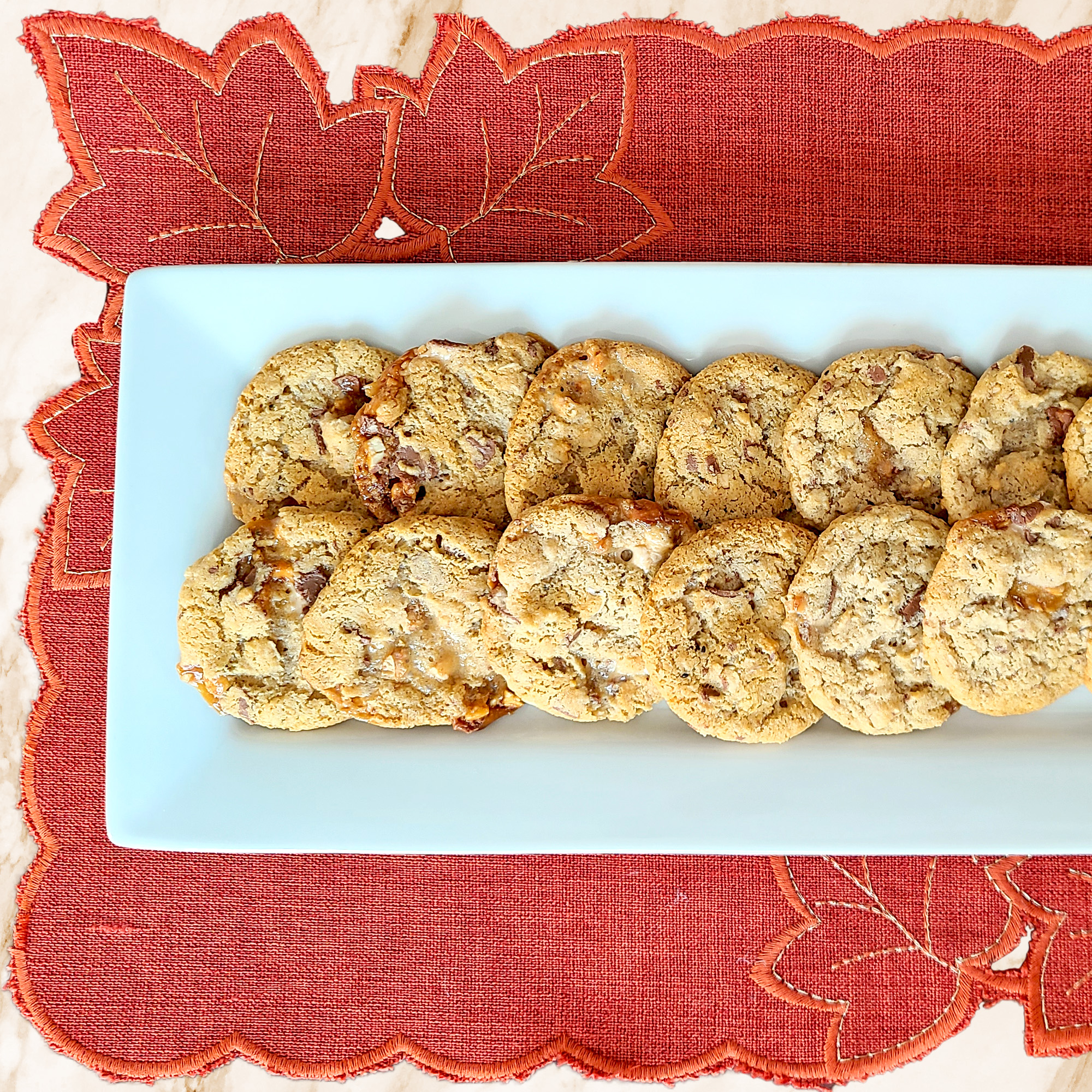 Gluten Free Snickers Cookies on a white platter with a rusty orange placemat underneath