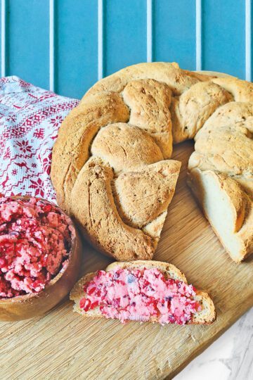 Braided Gluten Free Bread on a wooden cutting board with cranberry honey butter