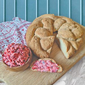 Braided Gluten Free Bread on a wooden cutting board with cranberry honey butter