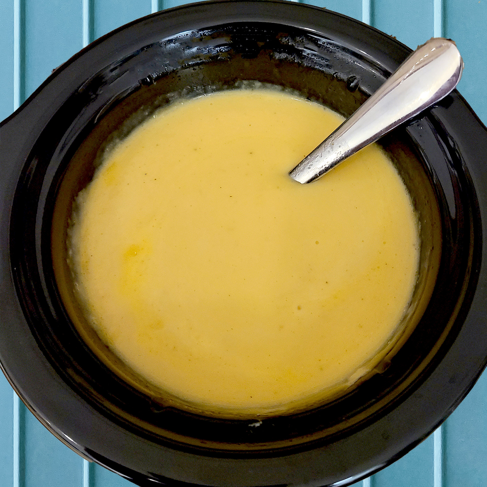 Homemade gluten free cheese dip in a small black crockpot