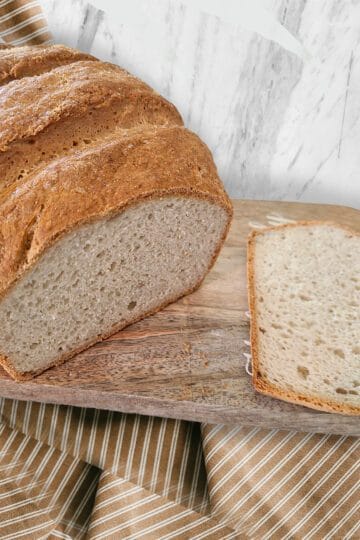 A gluten free loaf of bread sitting on a cutting board with one slice sliced off