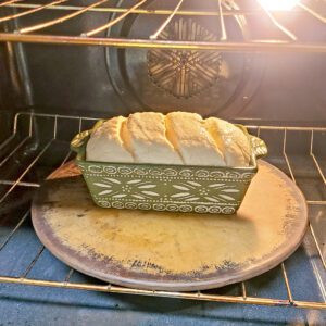 My gluten free loaf bread dough in ceramic pan sitting on a pizza stone in the oven