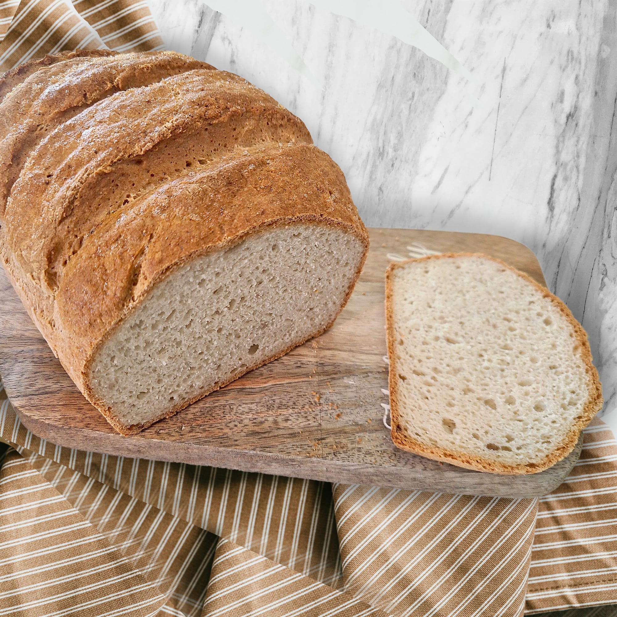 A gluten free loaf of bread sitting on a cutting board with one slice sliced off