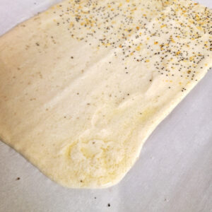 Gluten free sourdough discard batter spread on pan and sprinkled with toppings