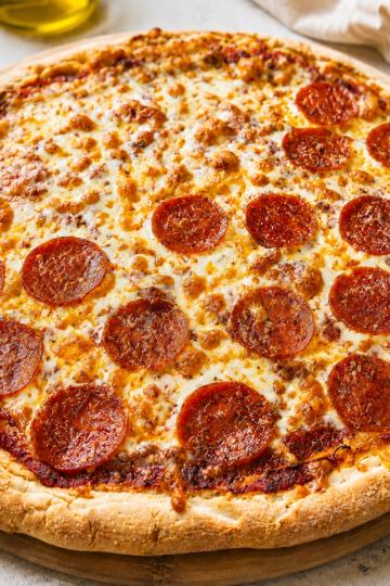 Sourdough discard gluten free pizza with cheese and pepperoni on a pizza stone