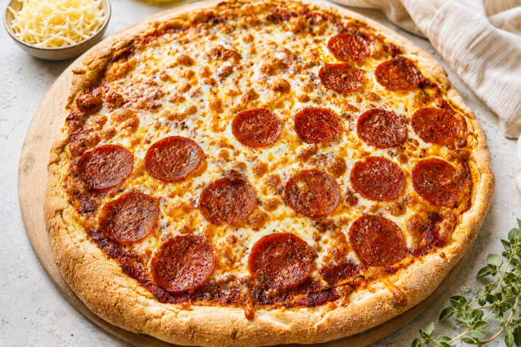 Sourdough discard gluten free pizza with cheese and pepperoni on a pizza stone