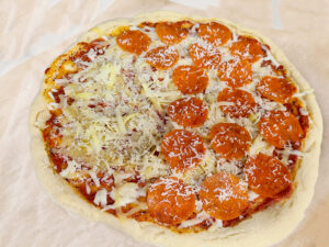 gluten free sourdough discard pizza crust with toppings added, ready to go back in the oven